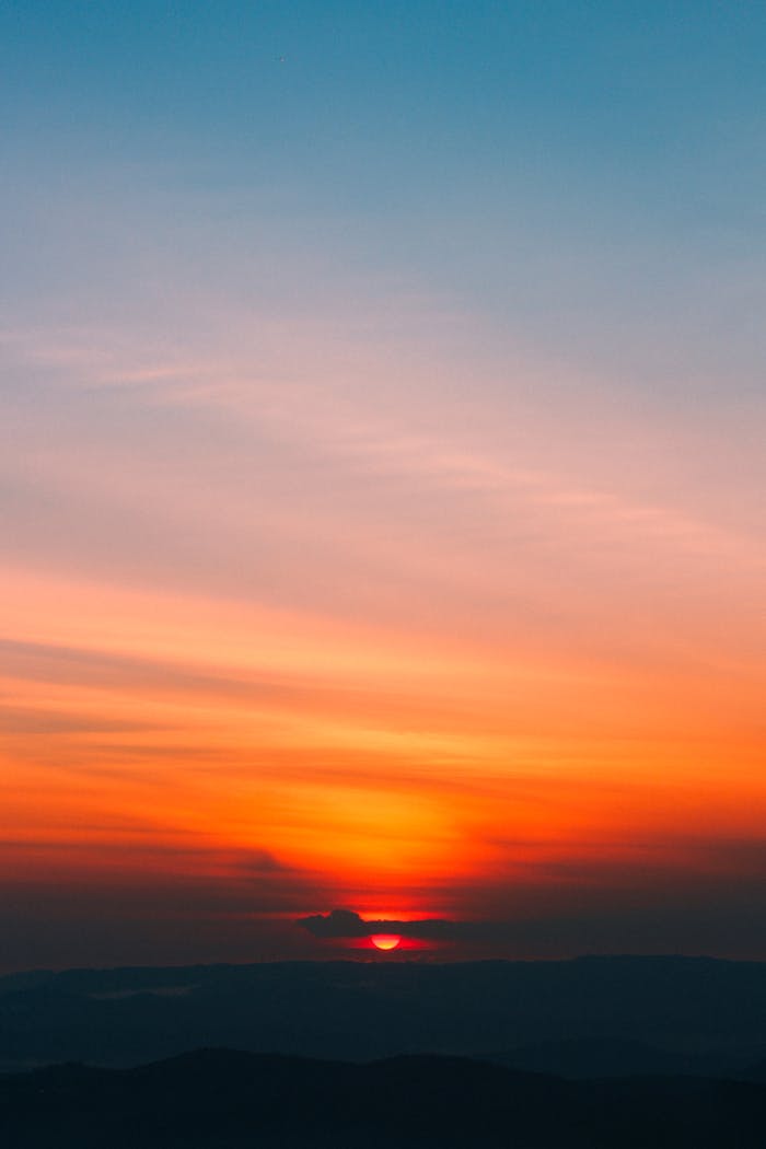 Dramatic sunrise with vibrant orange and blue hues painting the sky, creating a serene and peaceful scene.